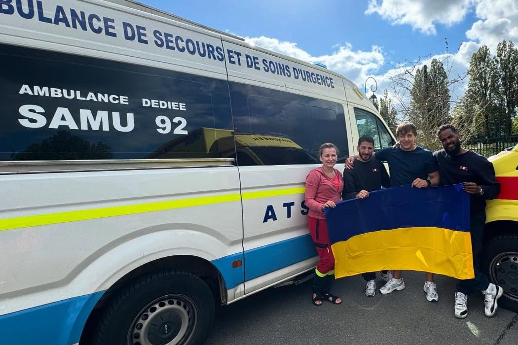 Команда фонду з українським прапором біля автомобілів швидкої допомоги
